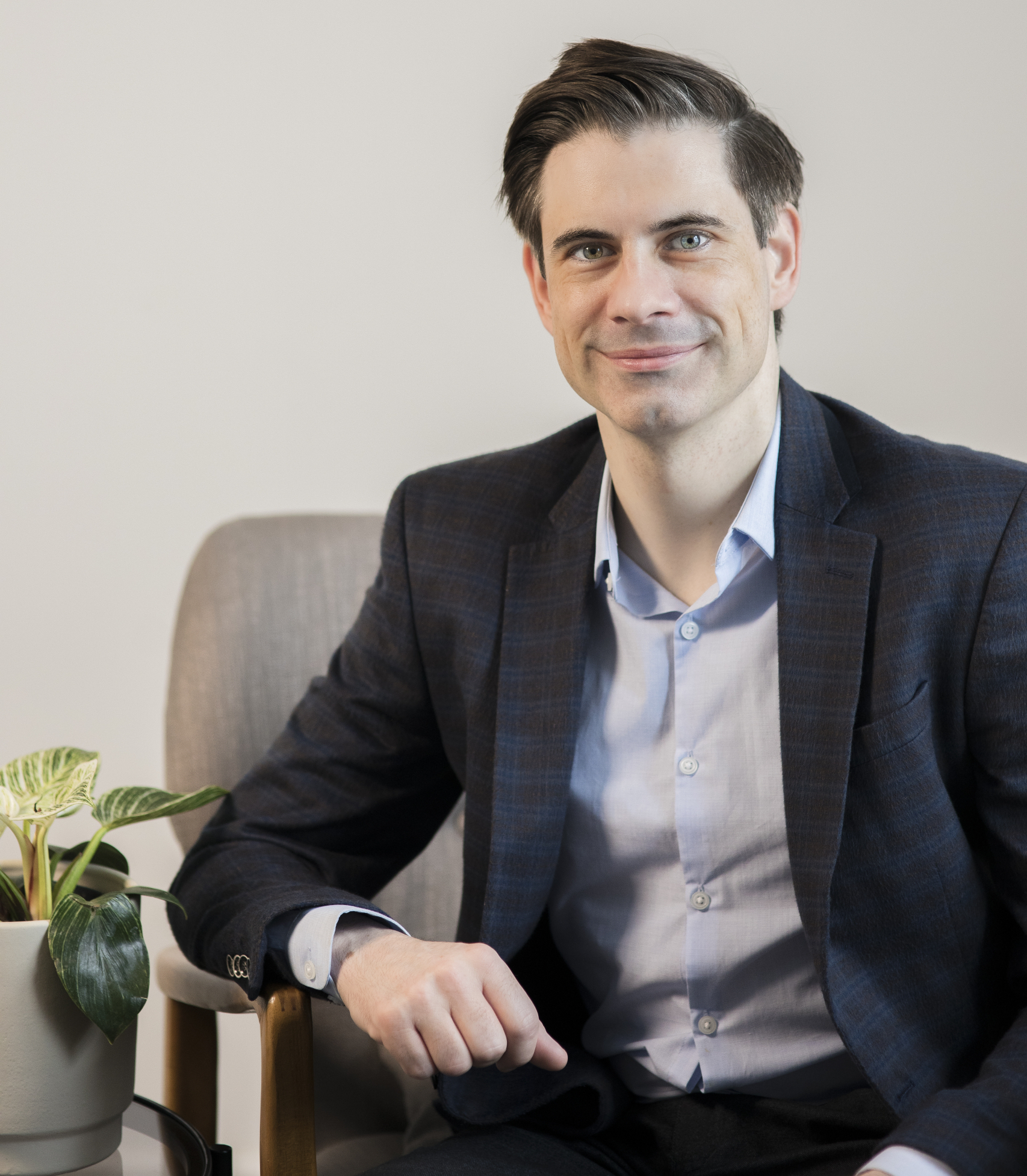 Male Call Agent in black suit sitting down beside flowers